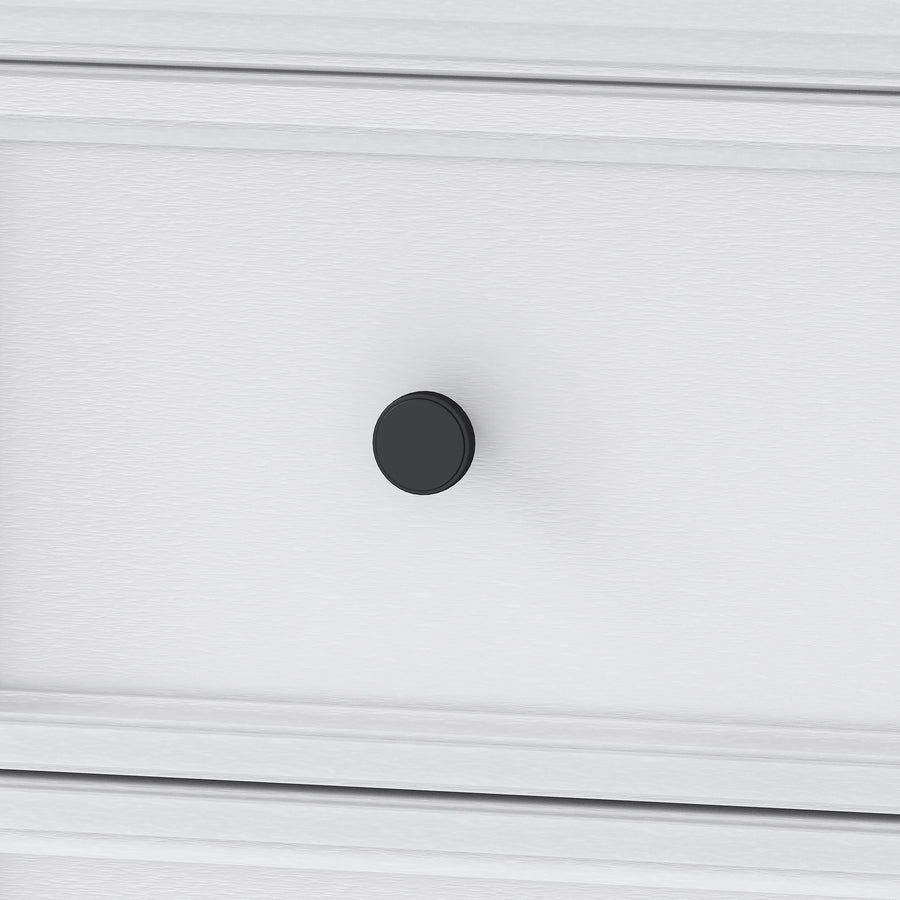 A close-up of a white drawer with a simple, round black knob in the center. The drawer has a subtle wood texture and clean, modern lines.