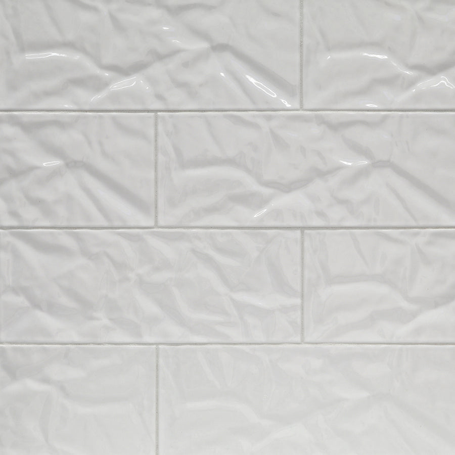 Shinju Mirai 3.5" x 9.5" Ceramic Tile in Paper features a glossy, crinkled texture and wavy, irregular surface that reflects light beautifully when arranged in a staggered brick pattern.
