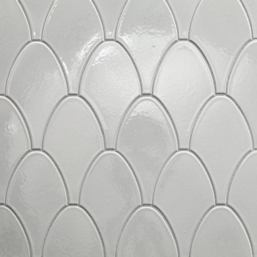 The Shinju Stringray Mosaic Tile in Kushi features glossy white tiles arranged in a repeating fish scale pattern, with subtle texture and raised edges, offering a clean, modern look and durable ceramic construction.