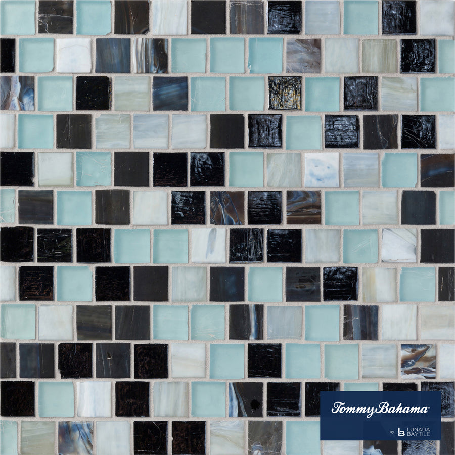 The Tommy Bahama Offset Mosaic Tile in Fujisan Mix features small square tiles in black, white, light blue, and iridescent shades—ideal for accent walls. The Tommy Bahama logo is displayed in the lower right corner.