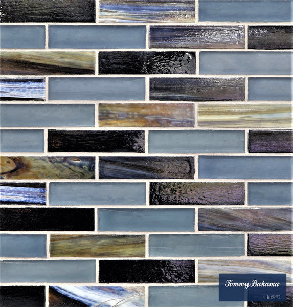 Tommy Bahama 0.85 sf/sh Brick Ceramic Tile in Aogashima Mix features rectangular tiles arranged in a staggered pattern with blue, black, and brown hues and a glossy, marbled finish. The Tommy Bahama logo appears in the bottom right corner.