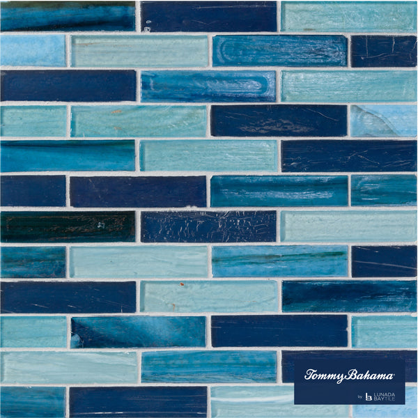 The Tommy Bahama 0.85 sf/sh Brick Ceramic Tile in Lucky Bay Mix features rectangular tiles in blue shades arranged in a brick pattern, with a small Tommy Bahama logo in the bottom right corner.