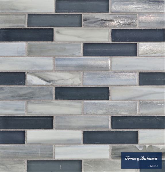 The Tommy Bahama 0.85 sf/sh Brick Ceramic Tile in Twillingate Mix features gray, blue, and white rectangular mosaic tiles in a staggered brick pattern, with the Tommy Bahama logo on a navy blue label at the lower right corner.