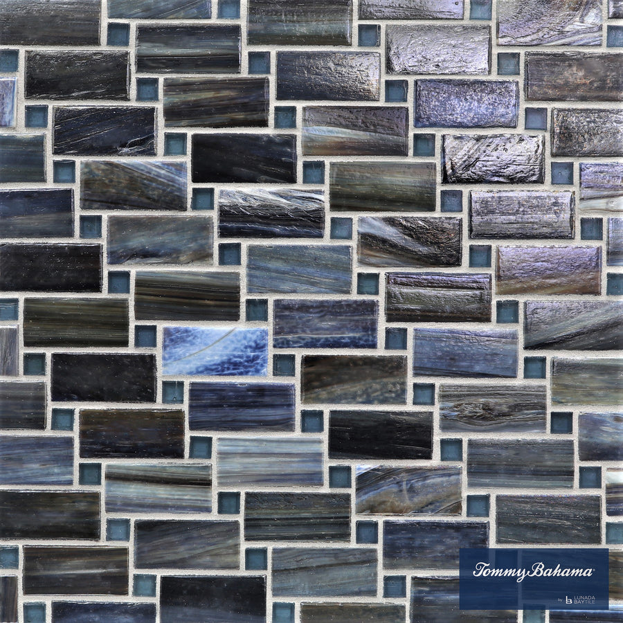 A close-up of the Tommy Bahama Vineyard Mosaic Tile in Aogashima Mix showcases rectangular glass tiles in blue, gray, and black shades—perfect for accent walls. The Tommy Bahama logo is visible in the lower right corner.