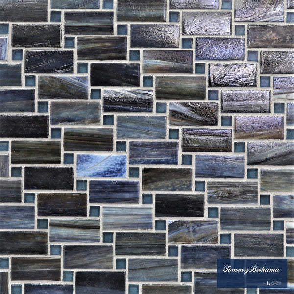 A close-up of the Tommy Bahama Vineyard Mosaic Tile in Aogashima Mix showcases rectangular glass tiles in blue, gray, and black shades—perfect for accent walls. The Tommy Bahama logo is visible in the lower right corner.