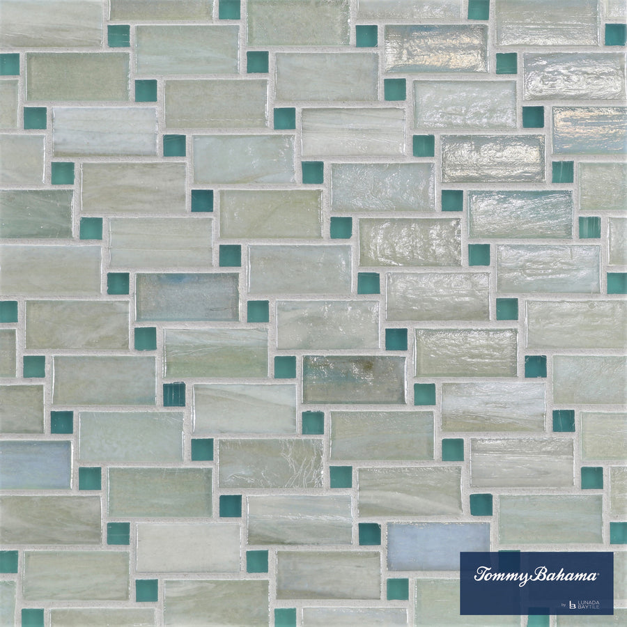 The Tommy Bahama Vineyard Mosaic Tile in San Blas Mix features rectangular ceramic tiles in white, gray, and light teal with an offset pattern—ideal for accent walls. The Tommy Bahama logo is shown in the bottom right corner.