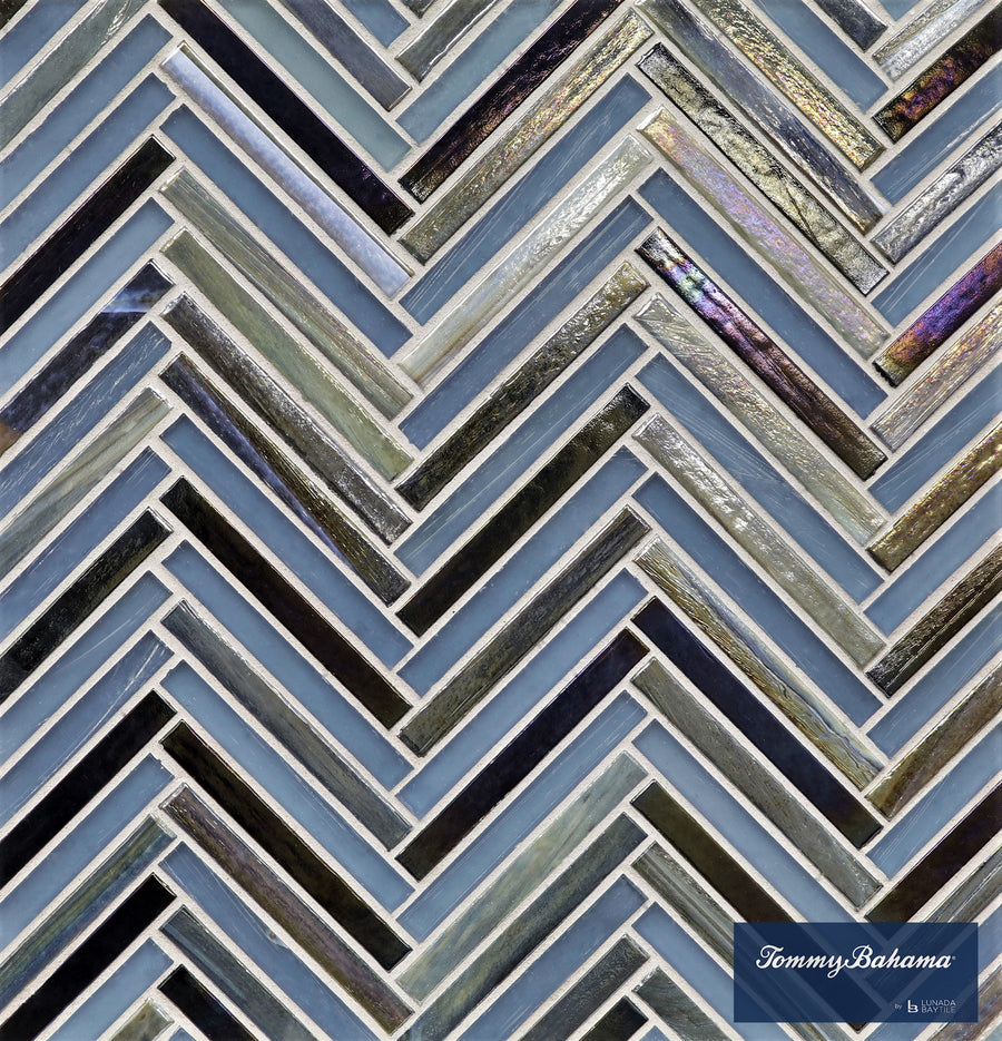A close-up of the Tommy Bahama Zig & Zag Mosaic Tile in Aogashima Mix showcases a blue, gray, and iridescent herringbone pattern—ideal for accent walls. The Tommy Bahama by Lunada Bay Tile logo is visible in the bottom right corner.