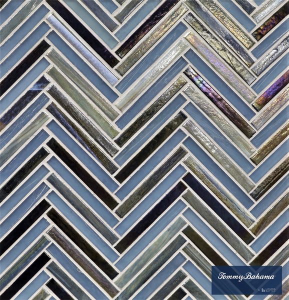 A close-up of the Tommy Bahama Zig & Zag Mosaic Tile in Aogashima Mix showcases a blue, gray, and iridescent herringbone pattern—ideal for accent walls. The Tommy Bahama by Lunada Bay Tile logo is visible in the bottom right corner.