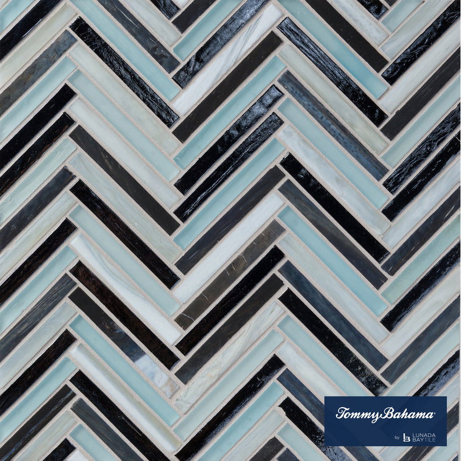 A close-up of the Tommy Bahama Zig & Zag Mosaic Tile in Fujisan Mix, showcasing a herringbone pattern with black, white, and light blue glass tiles. The Tommy Bahama logo appears at the bottom right corner.