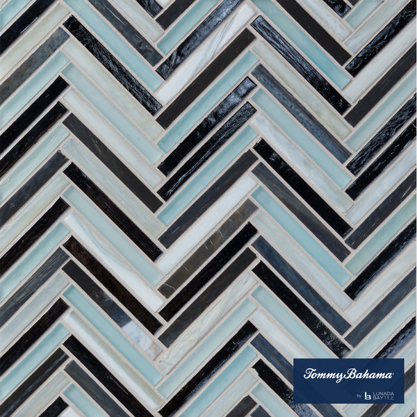 A close-up of the Tommy Bahama Zig & Zag Mosaic Tile in Fujisan Mix, showcasing a herringbone pattern with black, white, and light blue glass tiles. The Tommy Bahama logo appears at the bottom right corner.