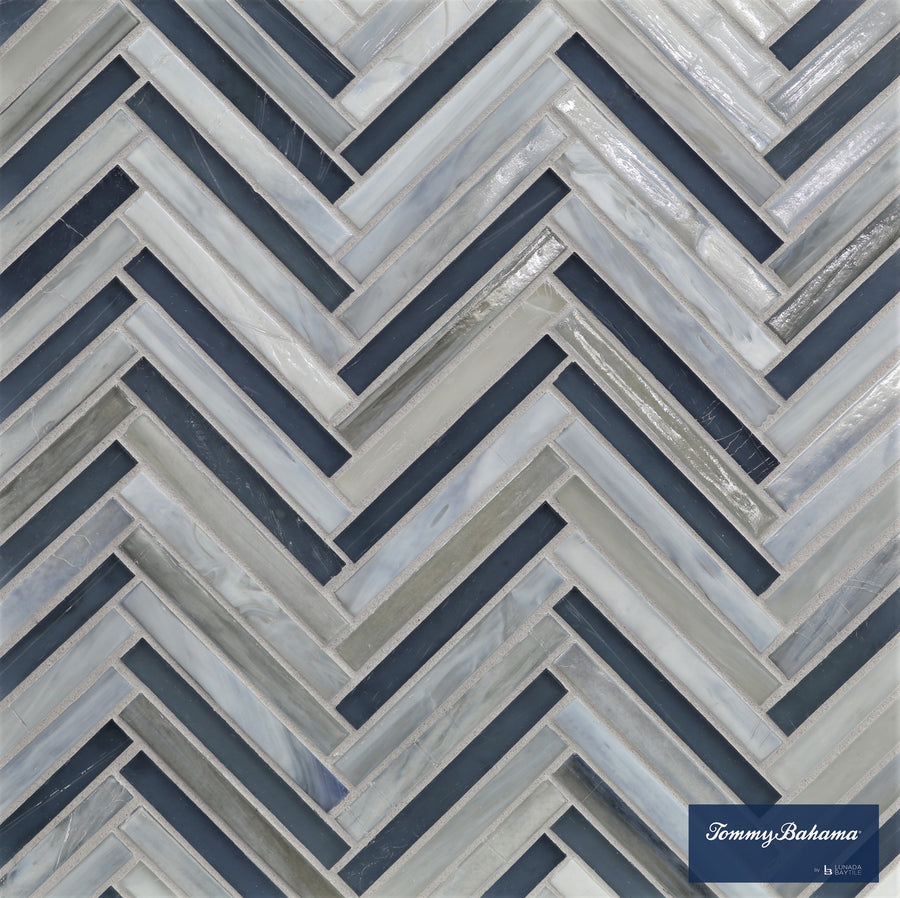The Tommy Bahama Zig & Zag Mosaic Tile in Twillingate Mix features a chevron zig zag pattern in blue, gray, and white with a glossy finish. A small Tommy Bahama by Lunada Bay Tile logo is in the bottom right corner.