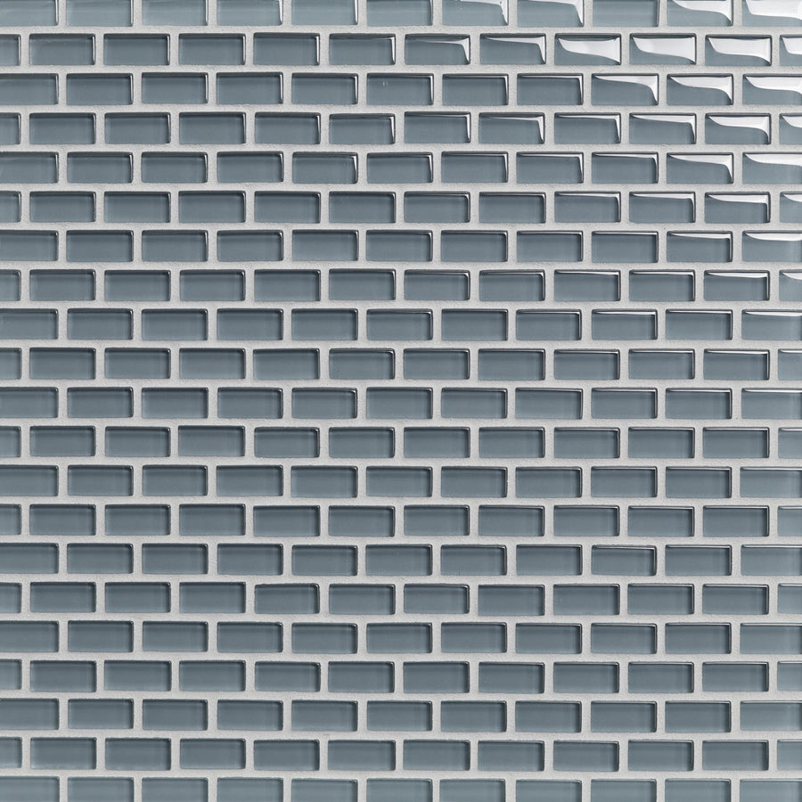 Close-up of a wall covered with Tomei Mini Brick Mosaic Tile in Natural, arranged in a staggered brick pattern—ideal for ceramic tile backsplashes with visible grout lines highlighting each glossy light gray tile.