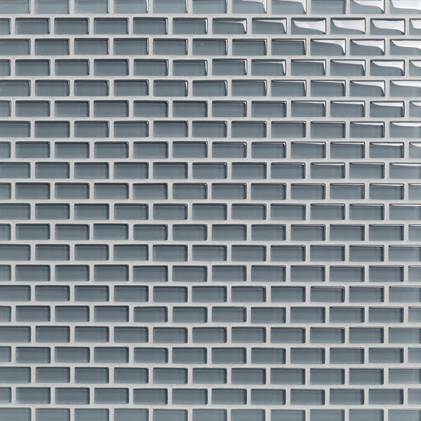 Close-up of a wall covered with Tomei Mini Brick Mosaic Tile in Natural, arranged in a staggered brick pattern—ideal for ceramic tile backsplashes with visible grout lines highlighting each glossy light gray tile.