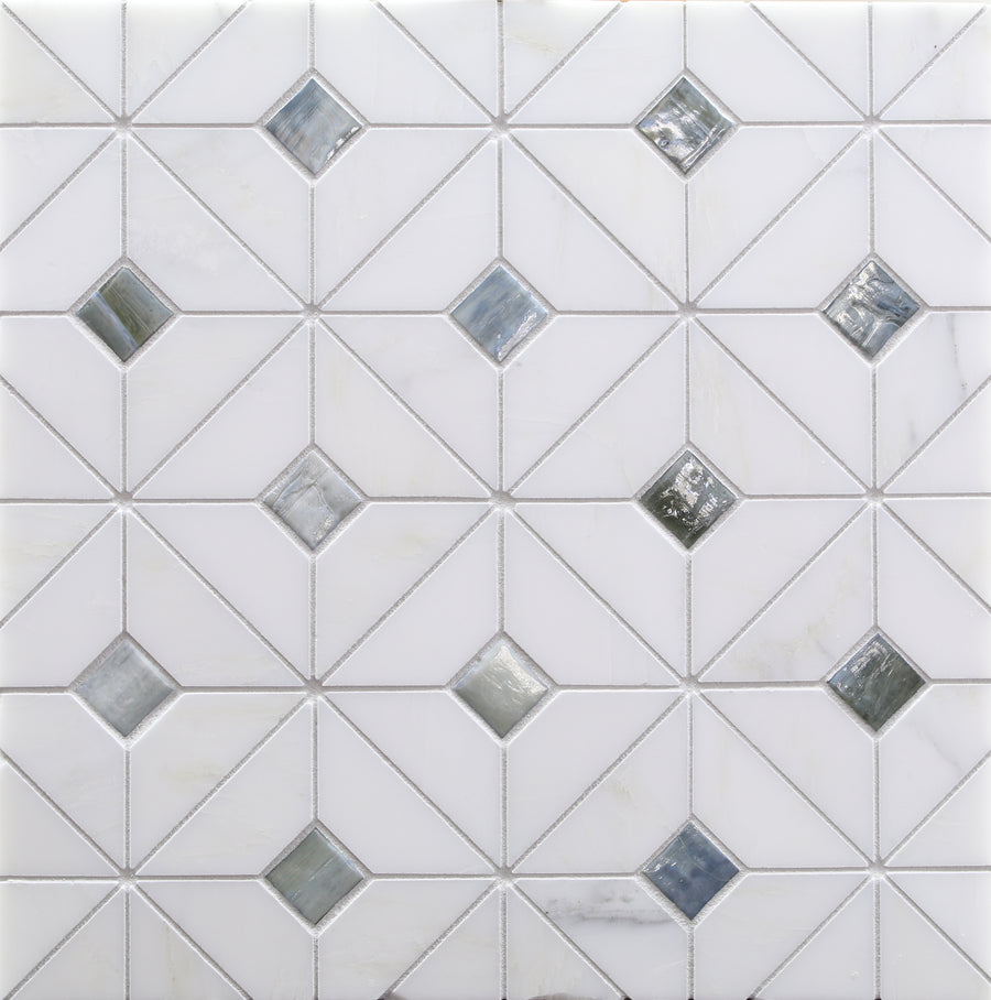 White tile wall with a geometric pattern of squares and triangles, featuring Vesuvio Quilt Mosaic Tile in Rock Garden—small reflective silver and gray diamonds—ideal for elegant backsplashes or striking accent walls.
