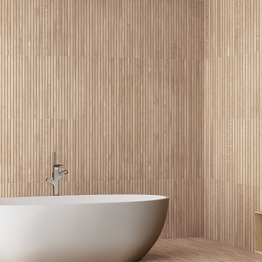 A modern bathroom featuring a white freestanding bathtub, a sleek silver faucet, and walls covered with vertical beige textured tiles.
