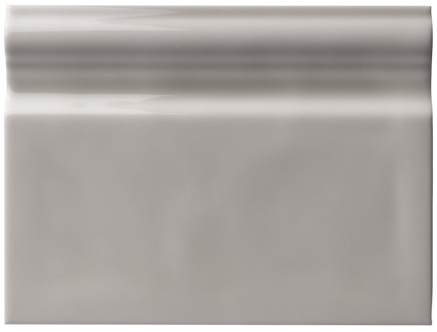 The Zephyr 6x8 Ceramic Baseboard features a rectangular, glossy light gray finish with a smooth, reflective surface and a raised, rounded top edge that adds handcrafted luxury and subtle highlights to any space.