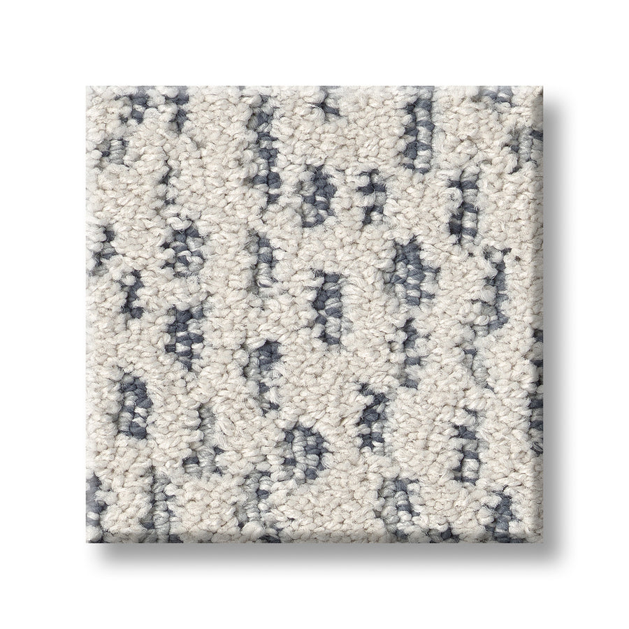 The Ambitious On Trend Carpet sample is a square, luxury carpet with a looped texture, cream background, and irregular dark gray and blue speckled patterns, displayed on a white surface.