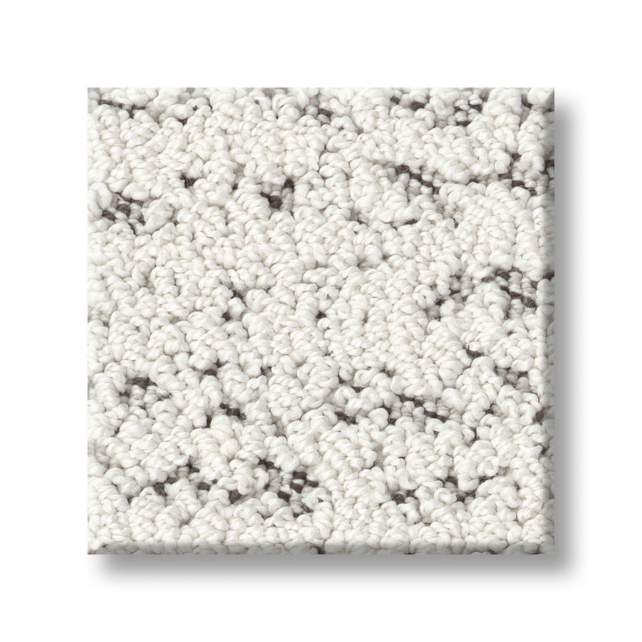 A square sample of Tangent On Trend Carpet displays its off-white, textured looped fibers with subtle gray speckles, highlighting the carpet's modern design and luxurious look against a white background.