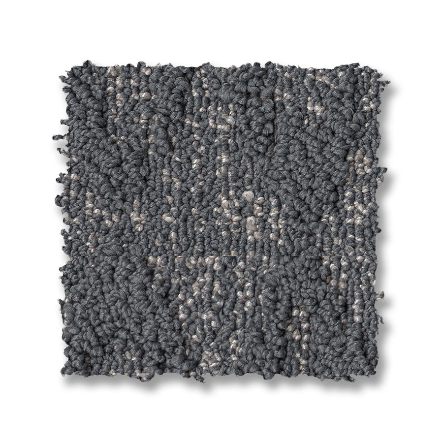A square swatch of Illumination On Trend Carpet, featuring a textured loop-pile pattern in gray and light beige tones, with a slightly irregular, chunky surface set against a white background.