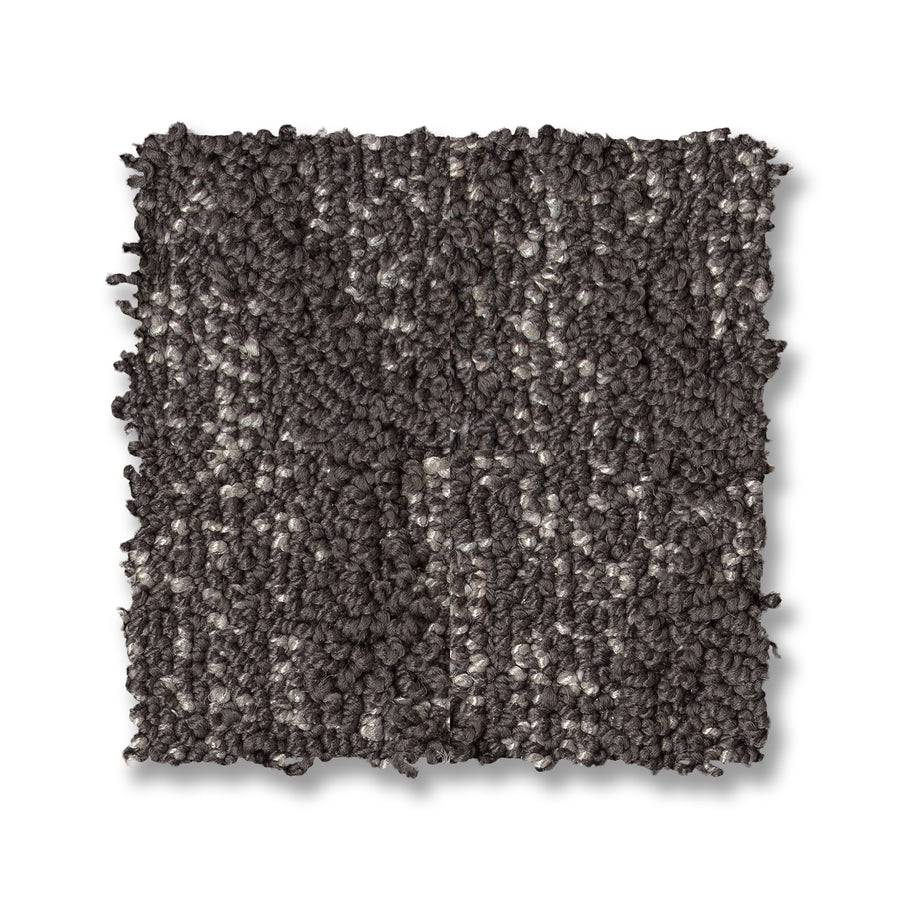 A square sample of Illumination On Trend Carpet, featuring loop-pile texture in gray and dark brown shades, displayed on a white background.