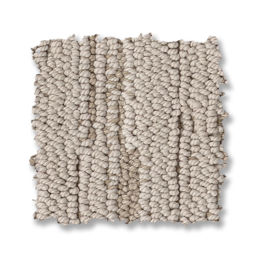 A close-up of the Loom Berber Carpet shows its chunky beige weave with thick, textured loops for a soft, cozy look and sophisticated style against a white background.
