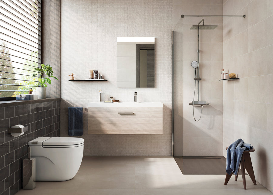 Modern bathroom with a wall-mounted sink, mirror, walk-in glass shower, white toilet, black tiles, a window with blinds, and minimalistic decor including towels, plants, and a stool.