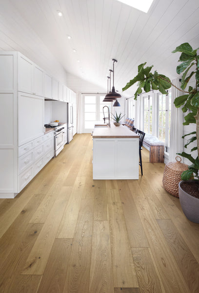 Bright kitchen featuring white cabinets, a spacious island with wooden countertop, pendant lighting, large windows, and Manchester 7 1/2