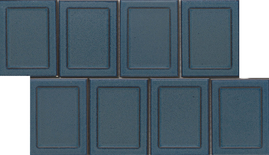 Eight Marco and Polo 4x5 Glossy Porcelain Tiles in Marco Blue, featuring a raised border and subtle speckles, are arranged in two staggered rows for a designer-inspired, brick-like layout.