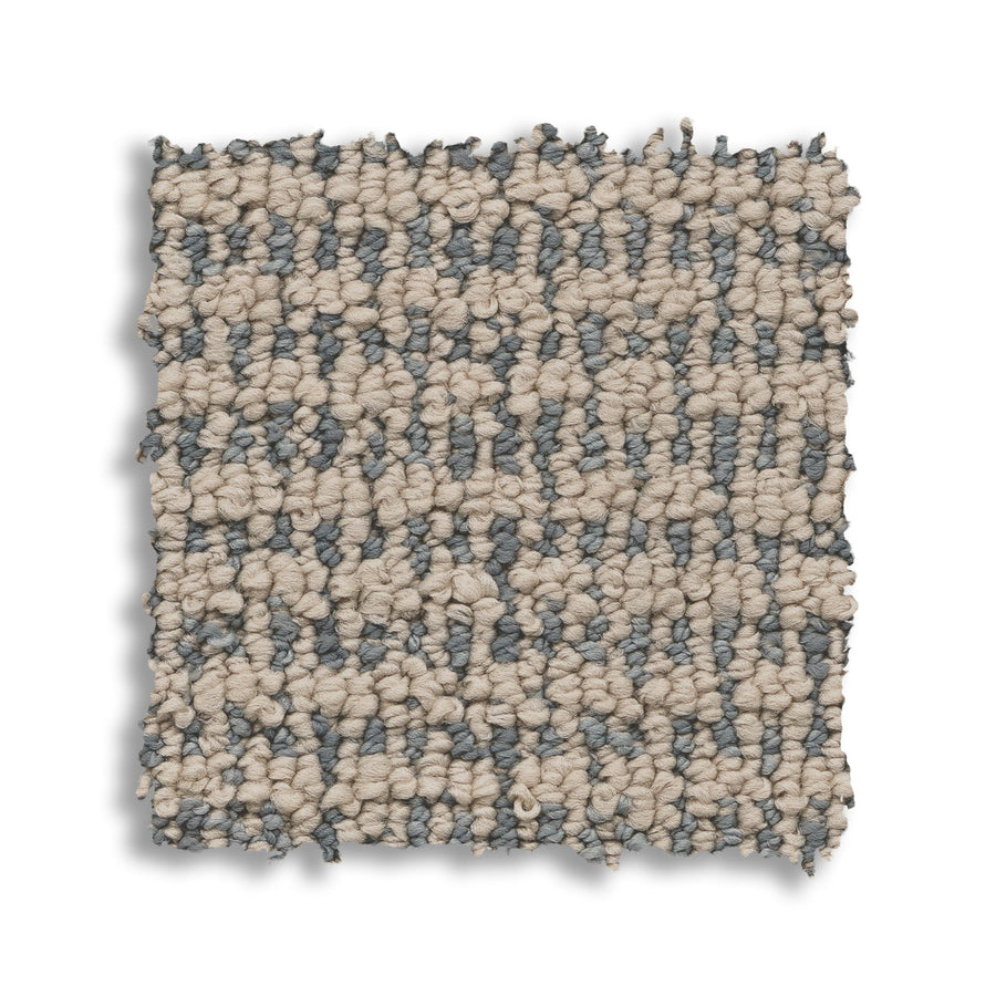 A square swatch of Laine On Trend Carpet displays a looped, checkered pattern in beige and gray fibers, creating a premium look on a white background.