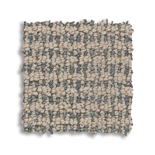 A square swatch of Laine On Trend Carpet displays a looped, checkered pattern in beige and gray fibers, creating a premium look on a white background.