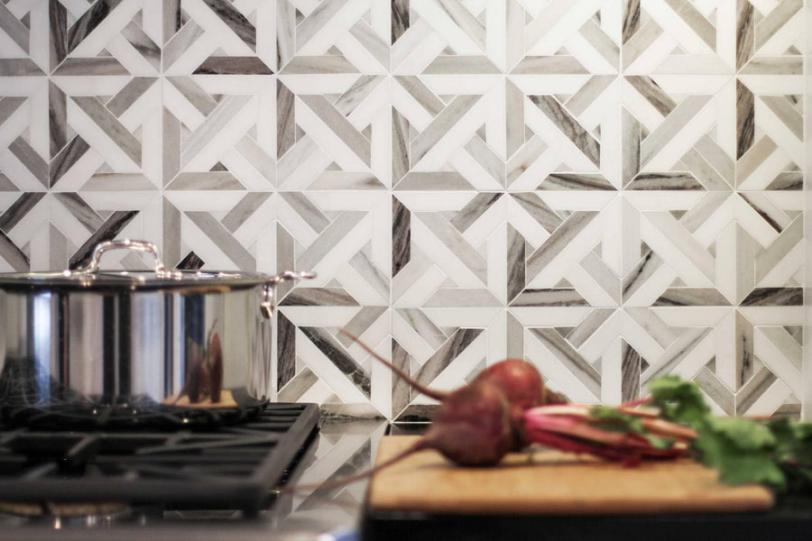 A kitchen scene with a geometric patterned tile backsplash, a stainless steel pot on a stove, and fresh beets with greens on a wooden cutting board in the foreground.