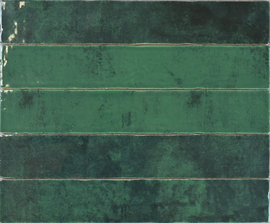 Five Marrakesh 2x16 Ceramic Tiles, rectangular and glossy green, arranged horizontally in a grid with subtly mottled coloring from dark emerald to light green and a gently textured surface.