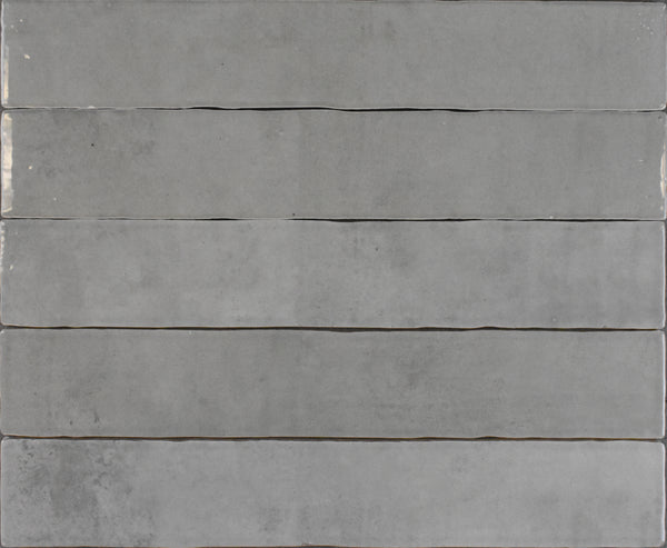 Six Marrakesh 2x16 Ceramic Tiles in grey are arranged horizontally, each featuring smooth, subtly varied tones and a textured surface for a minimalist, modern look.