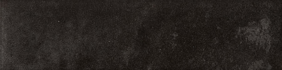The Menagerie 2.5x9.5 Porcelain Tile features a dark, textured surface with subtle gray variations and a handmade feel, offering the raw look of concrete or stone with added character and depth.