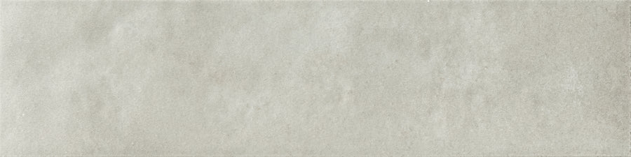 The Menagerie 2.5x9.5 Porcelain Tile features a smooth, light gray surface with a subtle handmade texture, giving it the appearance of concrete or stone.