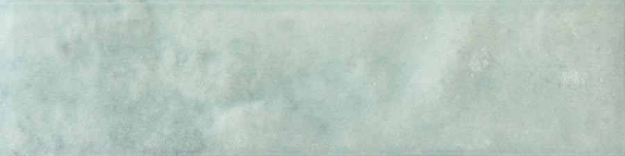 Menagerie 2.5x9.5 Porcelain Tile features a slightly glossy, pale blue-gray surface with soft tonal variations and handmade texture for a gentle, watercolor-inspired effect.