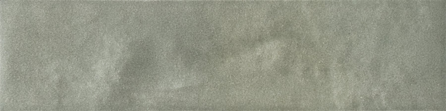 A close-up of the Menagerie 2.5x9.5 Porcelain Tile shows its smooth, pale gray surface with subtle handmade texture and gentle, uneven shading.