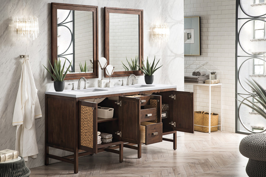 Double sink bathroom vanity with dark wood cabinets, two large mirrors, and potted plants. Cabinet doors and drawers are open, showing storage baskets and towels. The room has white walls and natural light.