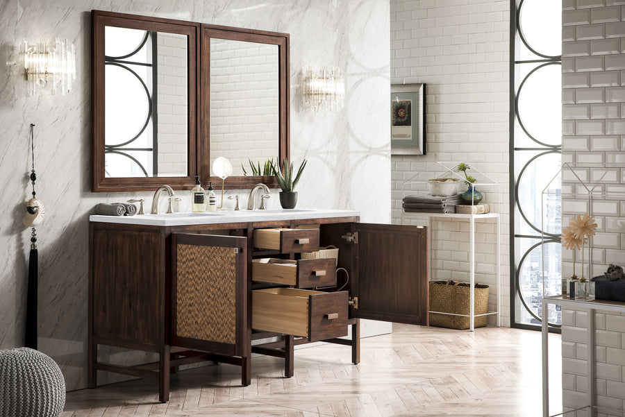 Modern bathroom with dual sinks, wooden vanity with open drawers and cabinets, two mirrors, wall sconces, potted plants, and stacked towels on a white shelf against white tiled and marble walls.