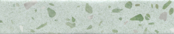 A close-up of the Fragmento 2x10 Ceramic Tile in Mint To Be shows a light green surface with scattered dark green and beige speckles, creating a bold terrazzo-inspired pattern reminiscent of decorative wall tiles.