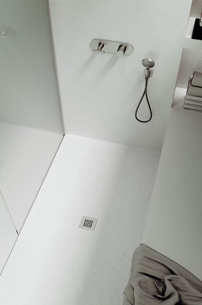 Minimalist bathroom with modern overhead and handheld showers, wall-mounted fixtures, folded towels on a shelf, and the NEOStone Point Center Drain Shower Base. Clean lines and a neutral palette finish the sleek, low-profile design.