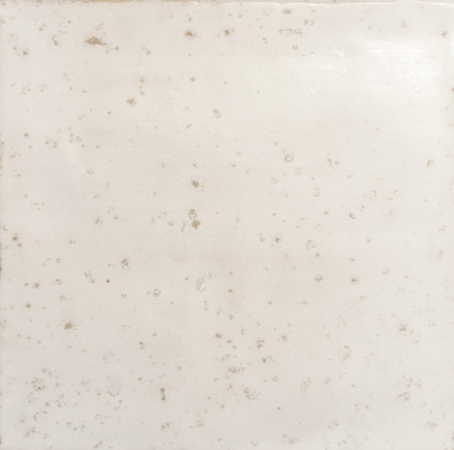 The Nakama 5" x 5" Ceramic Tile in Ivory features a square shape, uneven slightly glossy surface, and scattered small grayish-brown speckles for a weathered, aged look.