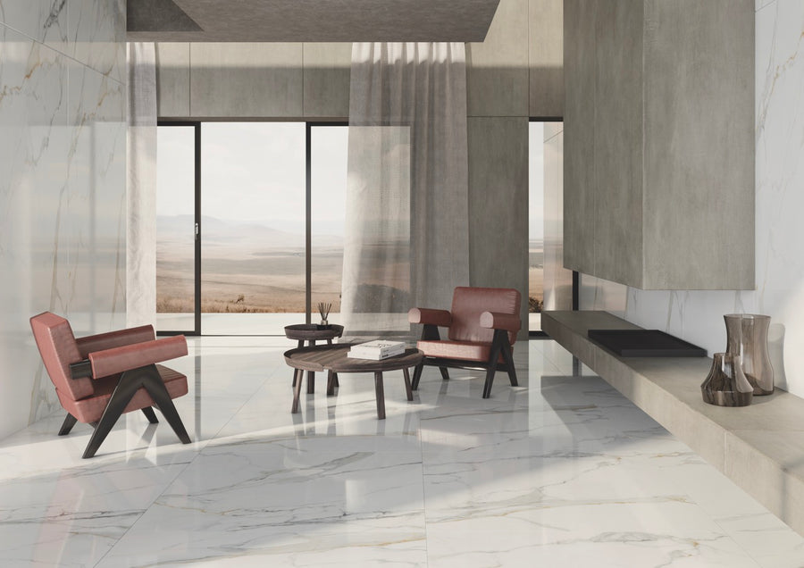 Modern minimalist living room with marble floors, beige walls, two red armchairs, and a round coffee table. Large windows with sheer curtains reveal a view of an open, arid landscape outside.
