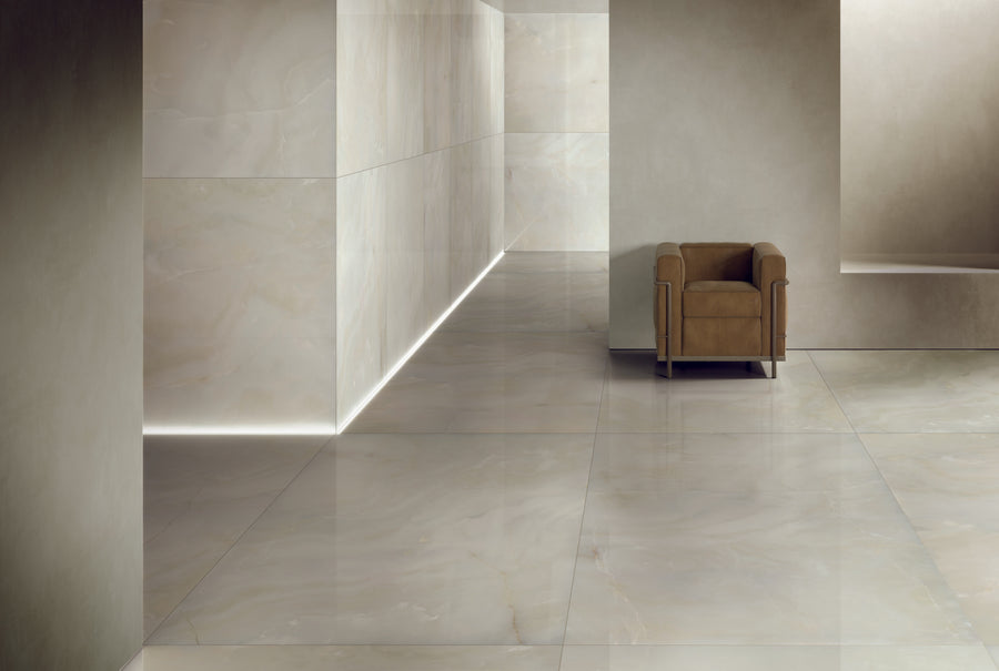 A minimalist interior with glossy, light marble floors and walls, soft lighting along the edges, and a single brown armchair placed near the corner. The space feels modern, clean, and spacious.