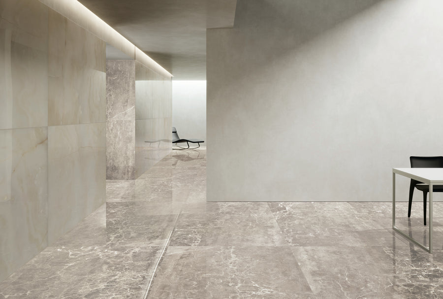 Minimalist interior with polished stone floors and walls, a hallway leading to a black lounge chair, and a white table with a black chair on the right side. The space is well-lit with modern ceiling lighting.
