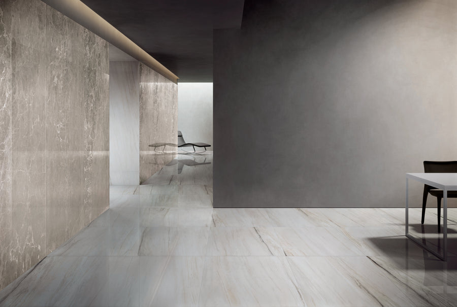 A modern, minimalistic interior with polished marble floors and walls, a gray table with a black chair on the right, and a lounge chair visible in a bright area at the back.