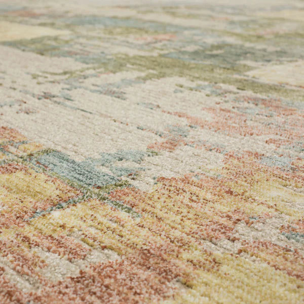 Close-up of a multicolored textured rug, featuring soft, abstract patterns in shades of beige, green, yellow, and peach. The fibers appear plush and slightly varied in height.