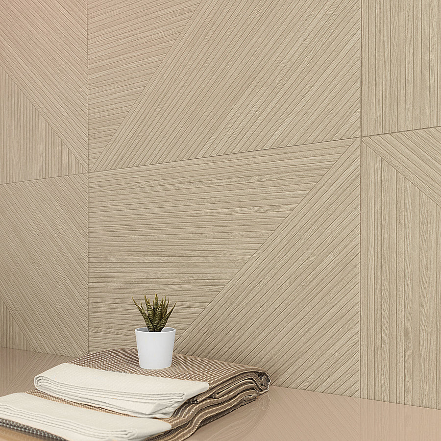 A neatly folded pair of beige and brown towels sits on a glossy surface next to a small potted succulent, with a beige, geometric-patterned wall in the background.