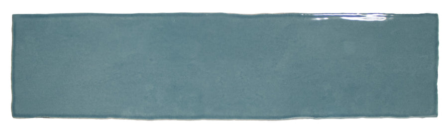 The Bali 3x12 Ceramic Subway Tile features a rectangular, glossy blue finish with slightly uneven edges and a smooth texture, bringing a luxurious touch to any room.