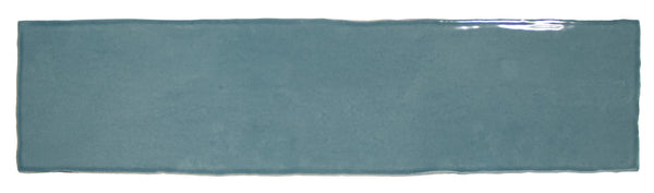 The Bali 3x12 Ceramic Subway Tile features a rectangular, glossy blue finish with slightly uneven edges and a smooth texture, bringing a luxurious touch to any room.
